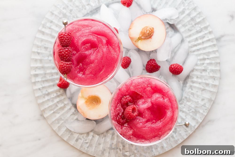 A frosty pink glass of Raspberry Peach Frosé, perfect for summer.