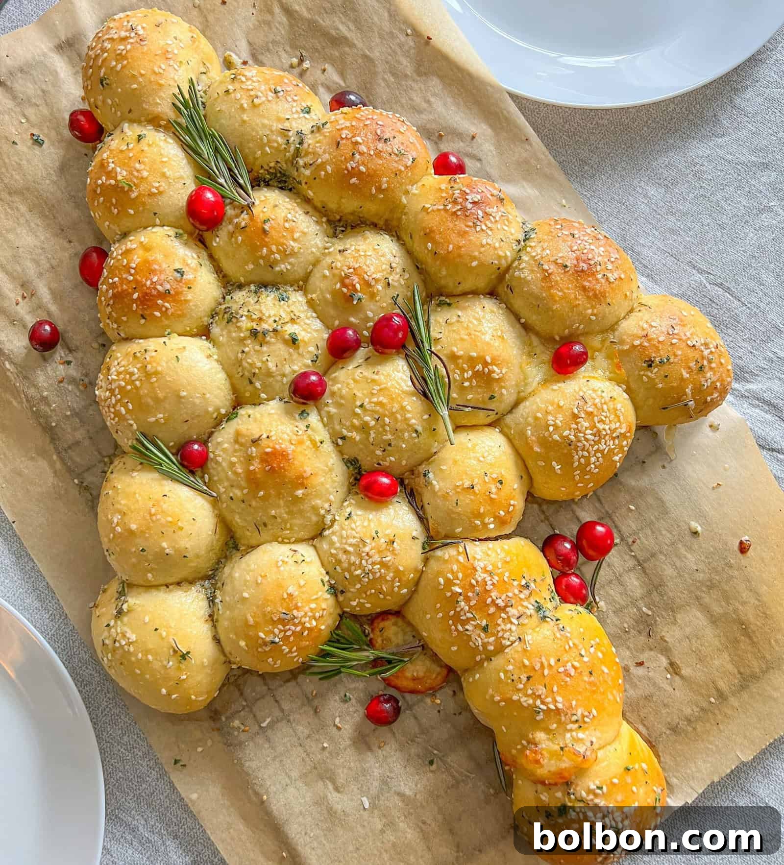 Garlic Bread Christmas Tree, a festive appetizer made from cheesy bread balls arranged in a tree shape and garnished with herbs, perfect for holiday gatherings.
