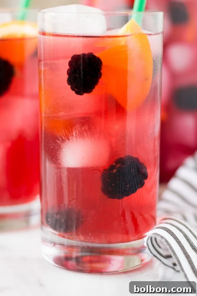 Close-up shot of Berry Sangria Iced Tea with ice, berries, and a straw, emphasizing its refreshing appeal.