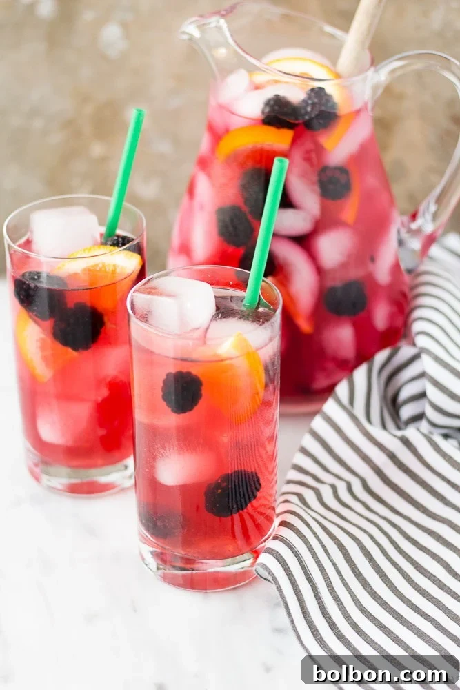Overhead shot of Berry Sangria Iced Tea with a pitcher of ingredients and fresh fruit on a rustic surface.