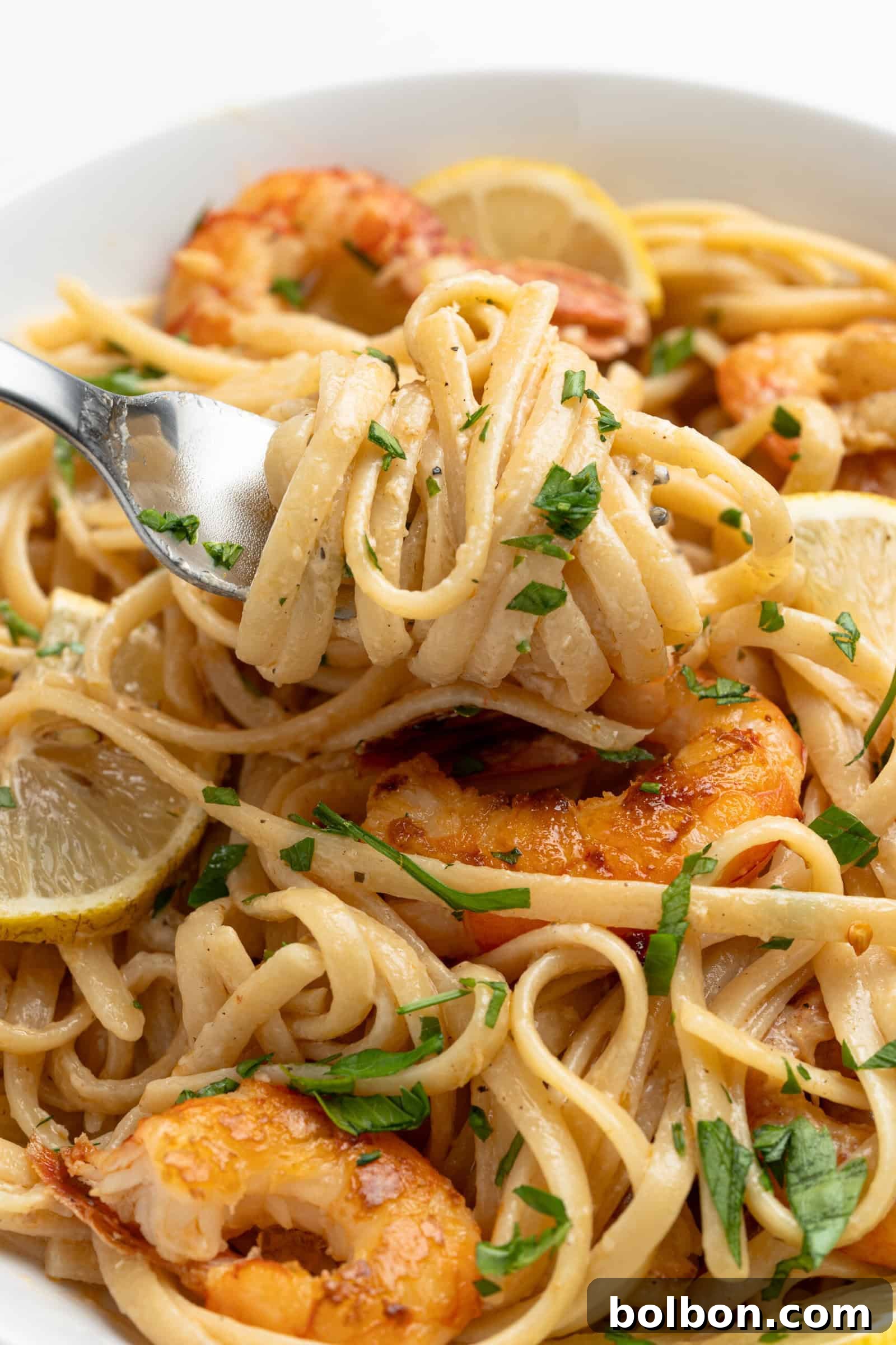 Zesty Lemon Garlic Shrimp Pasta 8 A close-up of a fork twirling linguine pasta with shrimp. The pasta is garnished with parsley and lemon slices, showcasing a creamy sauce. The shrimp are golden and cooked, adding texture and color to the dish.
