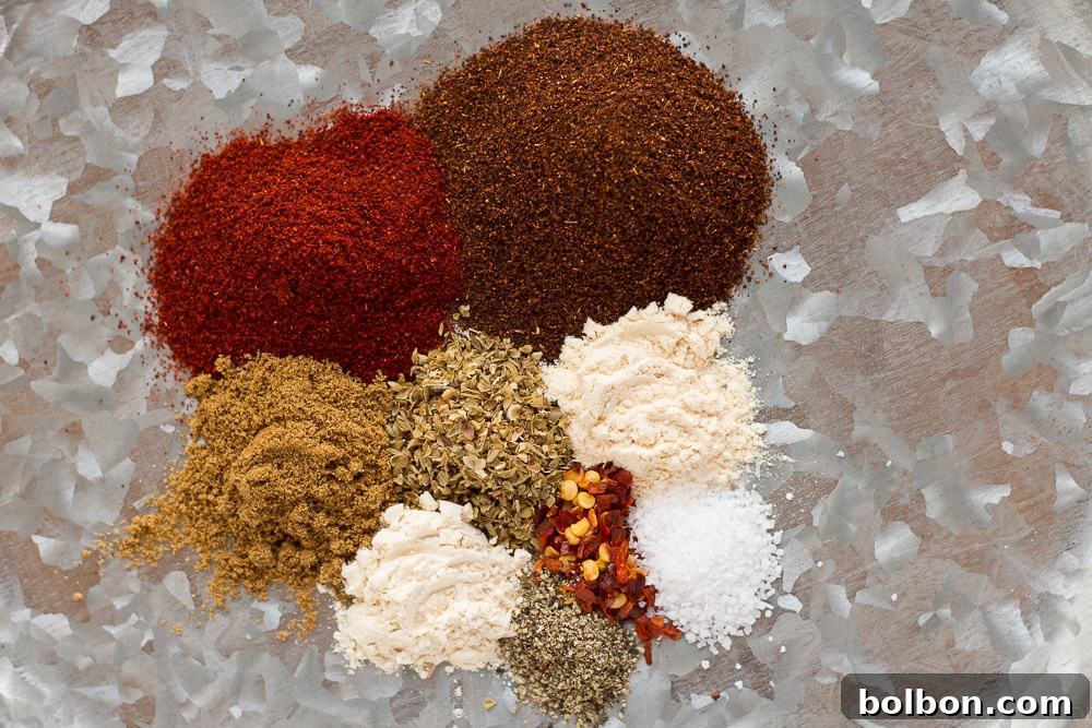 Homemade taco seasoning in a small jar, surrounded by fresh whole spices like chili, cumin, and oregano, suggesting natural ingredients.