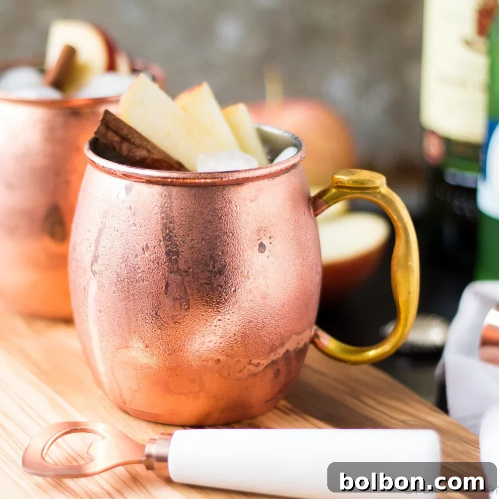 Orchard Spice Irish Mule 4 Ingredients for Apple Cider Irish Mule laid out: whiskey, apple cider, ginger beer, apples, cinnamon sticks