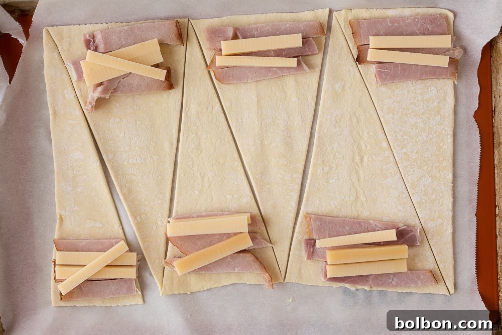 Several golden ham and cheese croissants arranged artfully on a white plate, ready to be served, highlighting their enticing crust.