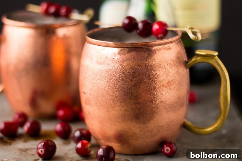 A beautifully garnished Cranberry Irish Mule in a copper mug, surrounded by fresh cranberries and festive decor, perfect for holiday celebrations.