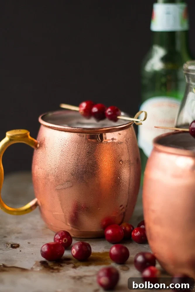 A vibrant Cranberry Irish Mule in a classic copper mug, garnished with fresh cranberries, ready to be enjoyed during the holiday season.