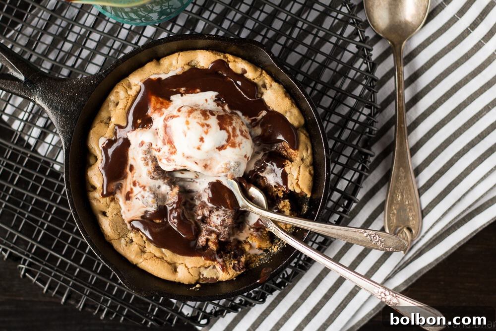 Warm Chocolate Chip Cookie Blondie Skillet Sundae with melted ice cream and chocolate sauce, served in a mini cast iron skillet.
