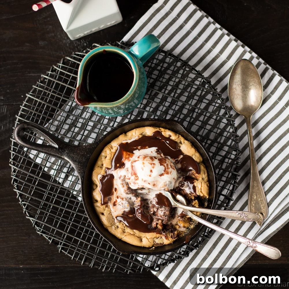 A beautifully presented Chocolate Chip Cookie Blondie Skillet Sundae with two spoons, emphasizing it's for sharing or a generous solo treat.
