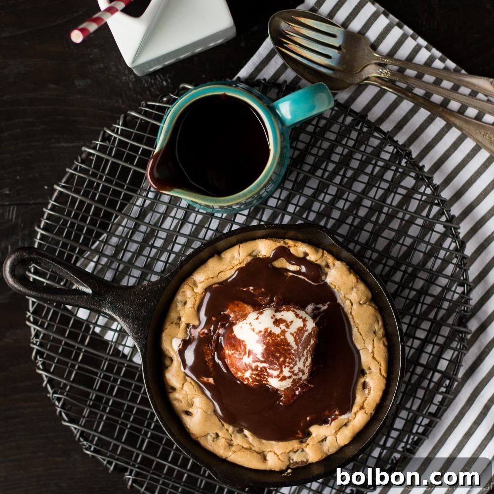 Close-up of a golden-brown chocolate chip blondie baking in a small cast iron skillet.