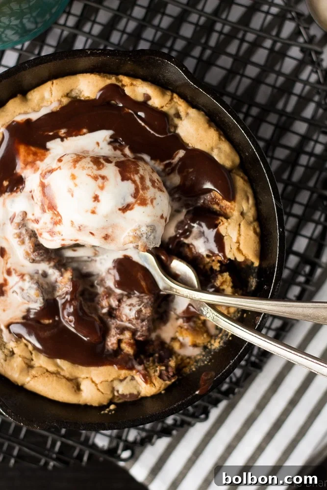 Chocolate chip blondie batter being spread evenly into a small cast iron skillet, ready for baking.