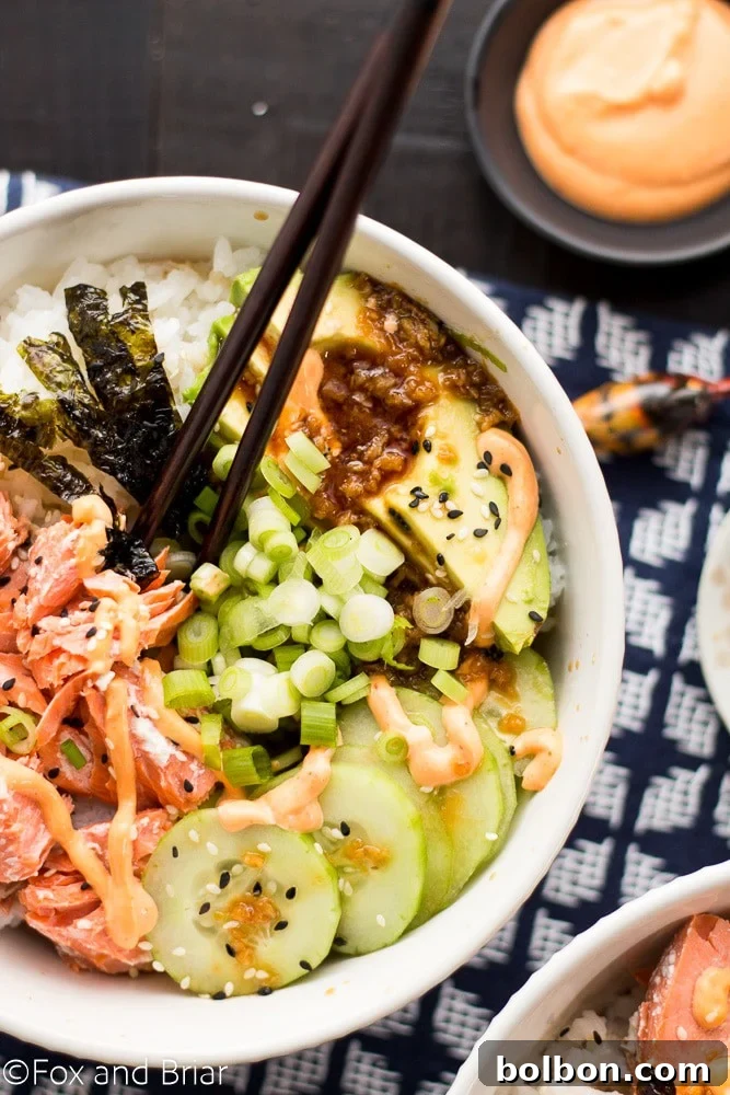 Delicious Salmon Sushi Bowl topped with spicy sriracha mayo, ginger soy dressing, and fresh herbs, ready to be enjoyed.
