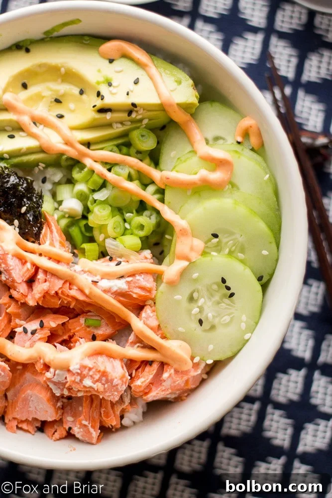 Hands preparing fresh Salmon Sushi Bowls, drizzling spicy sriracha mayo and ginger soy dressing over salmon, rice, and vegetables.