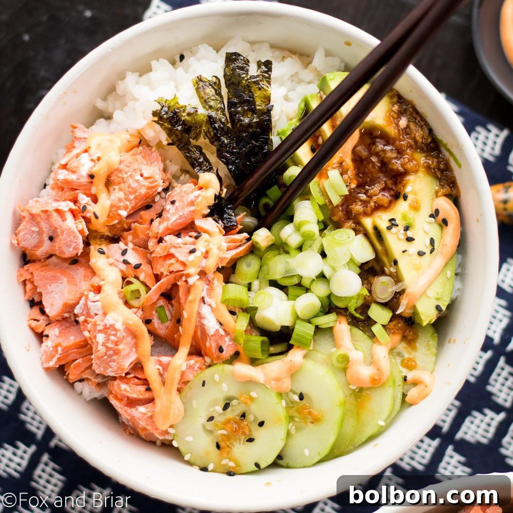 Assembling a Salmon Sushi Bowl with various fresh ingredients like avocado, cucumber, and green onions over perfectly cooked salmon and sushi rice.