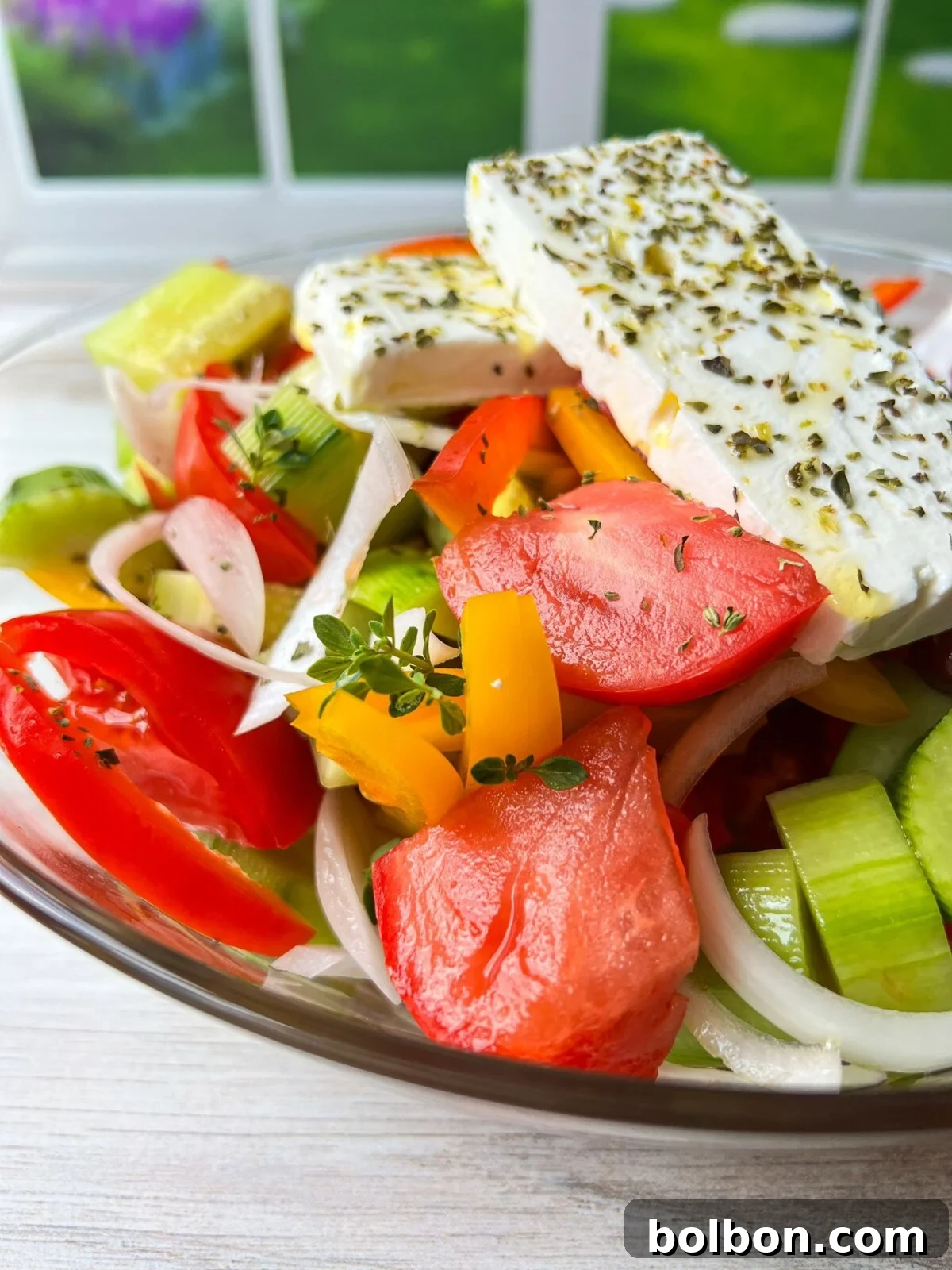 Authentic Greek Salad featuring fresh tomatoes, cucumbers, bell peppers, onions, Kalamata olives, and generous chunks of feta cheese.
