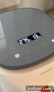 Close-up of a COSORI air fryer digital control panel displaying a temperature of 275°F and a timer set to 13 minutes. Several touch buttons and cooking presets are visible on the panel.