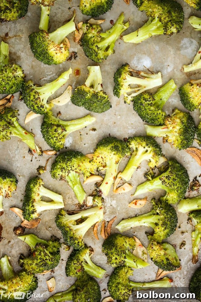Close-up of golden brown, caramelized lemon parmesan roasted broccoli florets on a baking sheet, fresh out of the oven