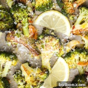 Close-up of lemon parmesan roasted broccoli with garlic slices and lemon wedges, ready to serve.