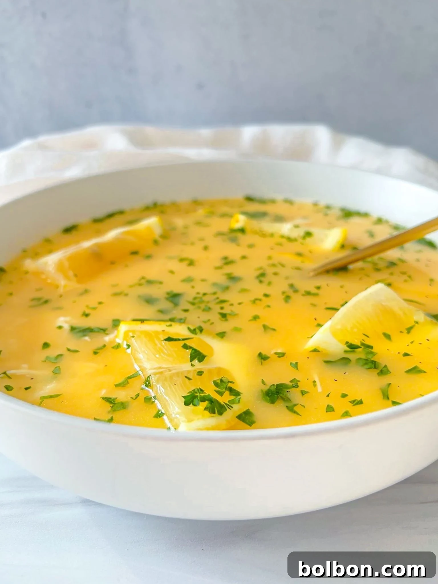 A bowl of vibrant Greek Lemon Soup, garnished with fresh parsley and lemon slices, promises a delightful culinary experience.