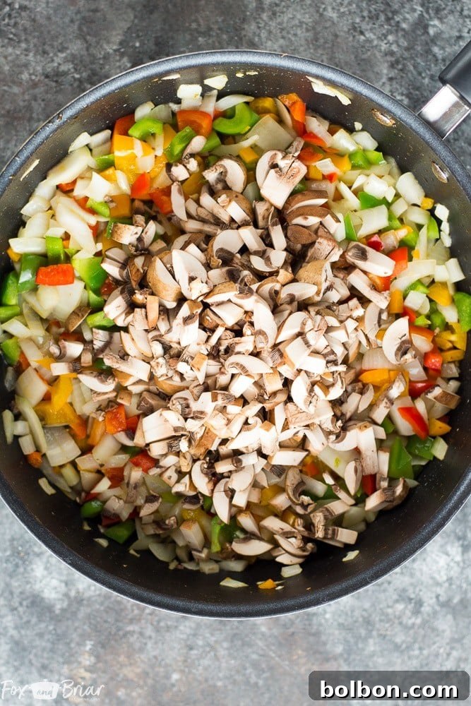 Freshly prepared ingredients for Pizza Stuffed Bell Peppers: ground Italian sausage, diced onions, garlic, and colorful bell peppers ready for filling.