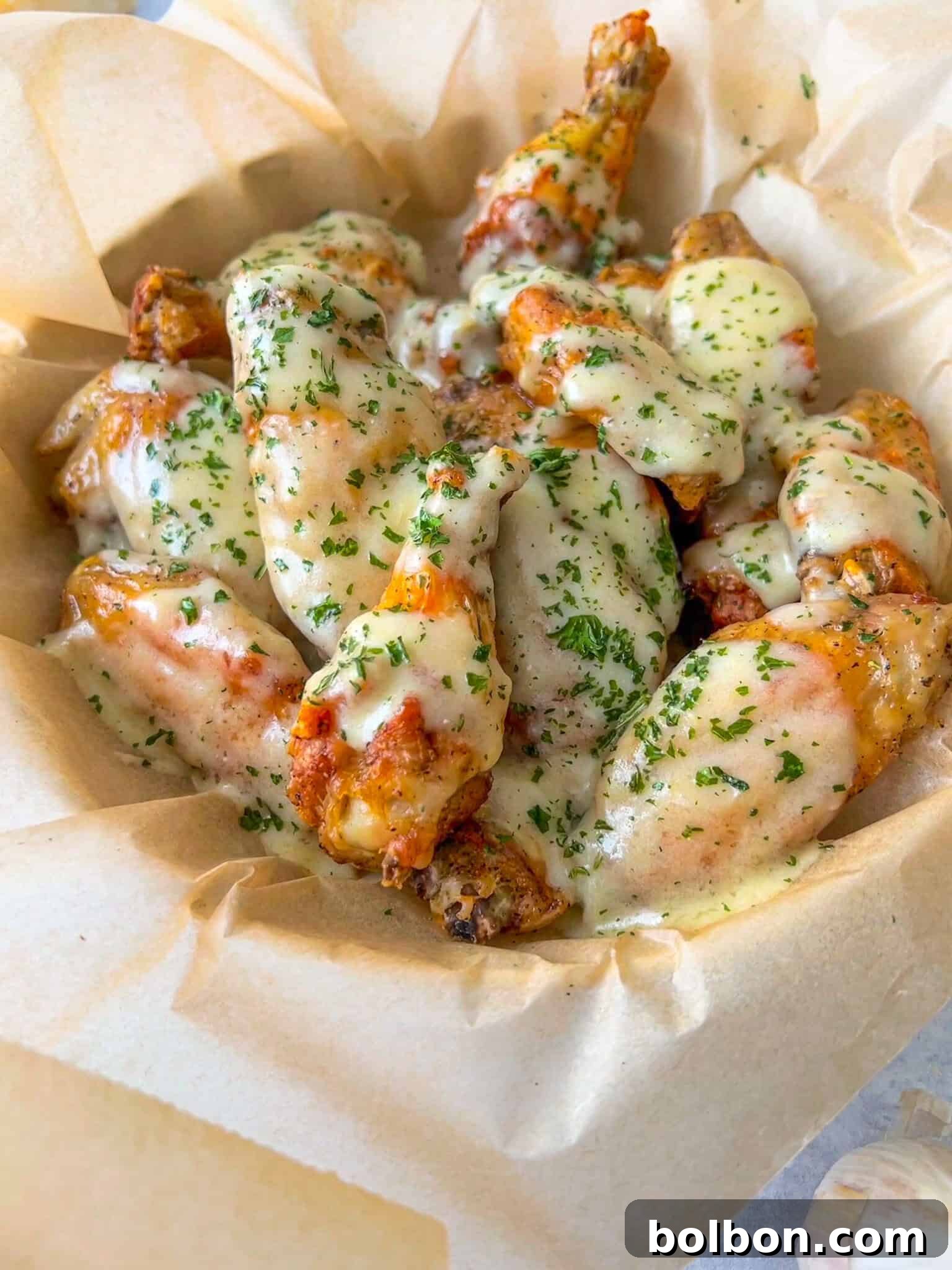 Irresistible Garlic Parmesan Wings 2 Garlic Parmesan Wings, golden brown and coated in a creamy white sauce, garnished with fresh herbs, ready to be enjoyed.