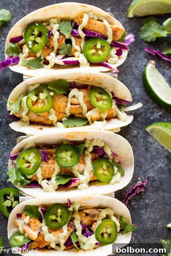 A beautifully plated Chipotle Lime Fish Taco, showcasing the vibrant colors of the slaw, the creamy avocado crema, and the fresh cilantro garnish.