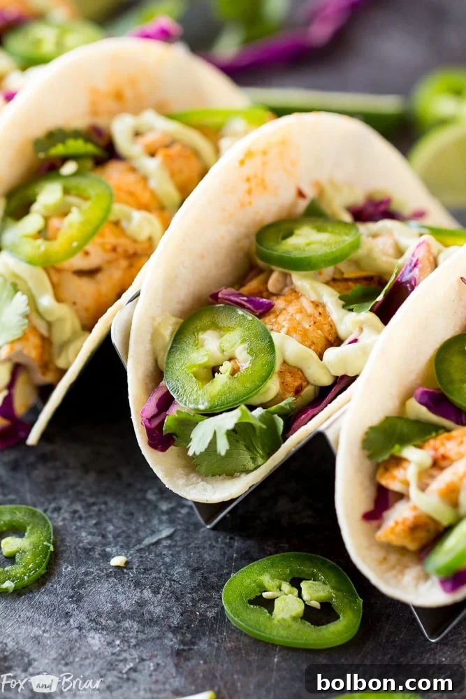 A vibrant and appetizing spread of all the components needed to assemble Chipotle Lime Fish Tacos: cooked fish, fresh slaw, creamy avocado crema, and warm tortillas.