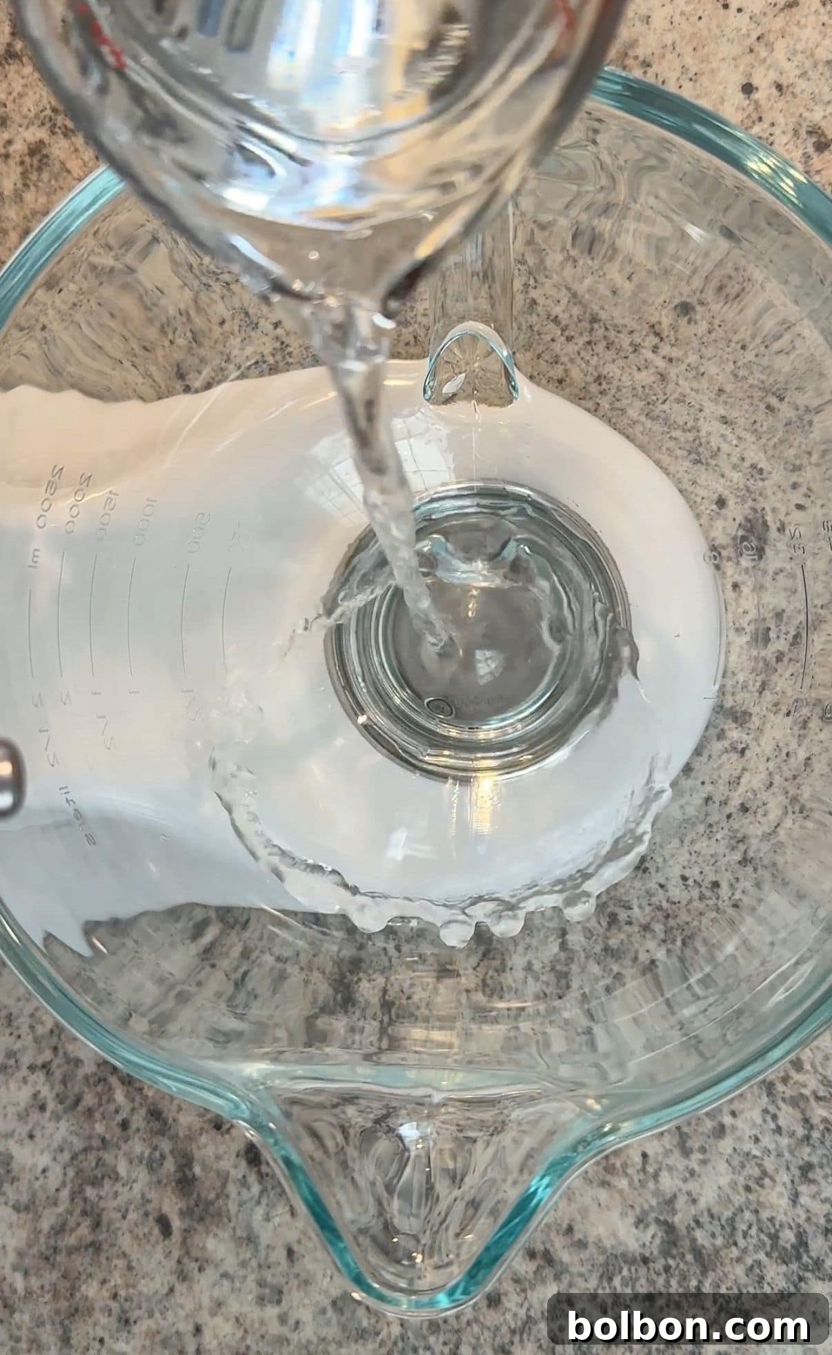 Close-up of egg whites whipping in a stand mixer, forming soft peaks.
