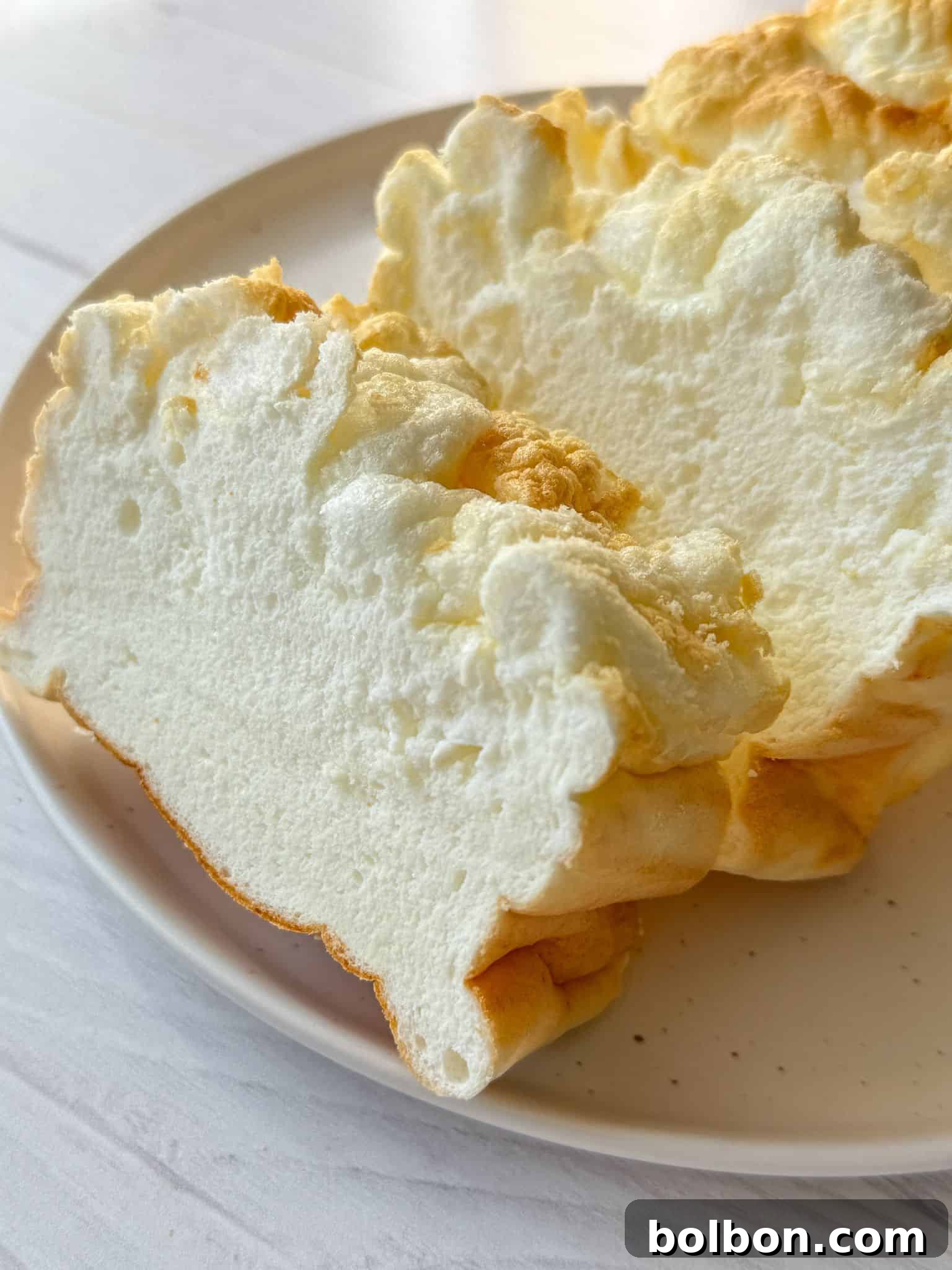 A beautifully baked and sliced loaf of Cloud Bread resting on a white plate, ready to be enjoyed.