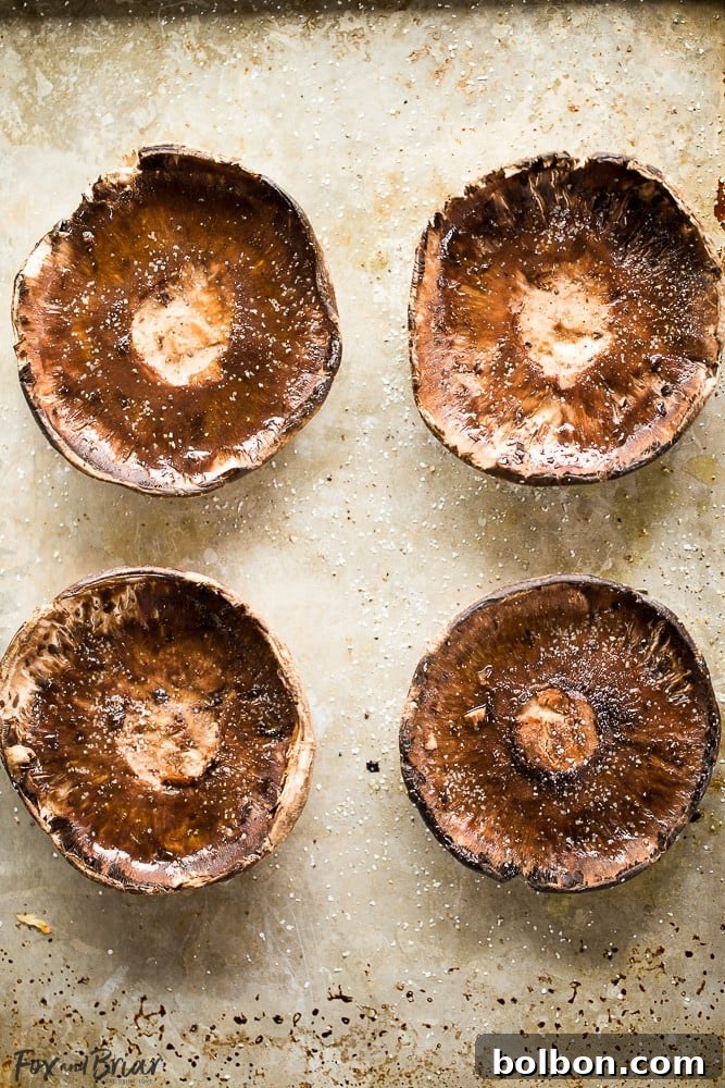 Gourmet Sausage Stuffed Portobellos 4 A cutting board displaying cooked sausage stuffed portobello mushrooms, garnished with fresh basil leaves.
