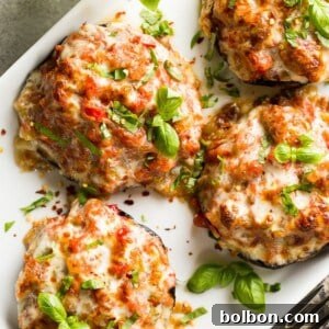 Gourmet Sausage Stuffed Portobellos 7 Close-up of a baked sausage stuffed portobello mushroom with melted cheese and fresh basil.