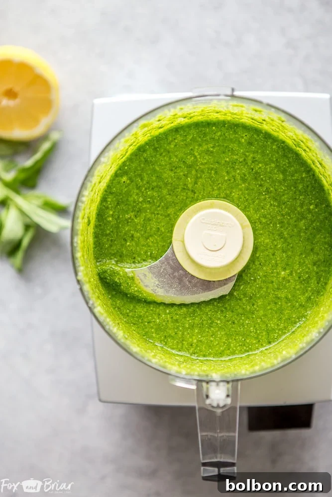 A food processor blending ingredients for homemade pesto, showing the emulsification process