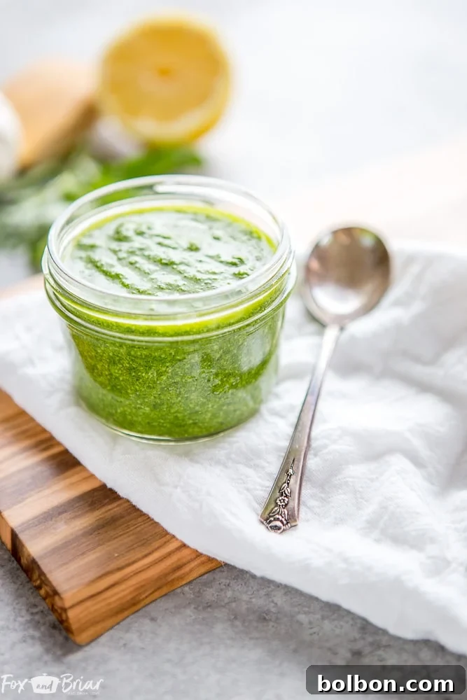 Two jars of homemade pesto, one with fresh basil leaves, on a rustic wooden surface