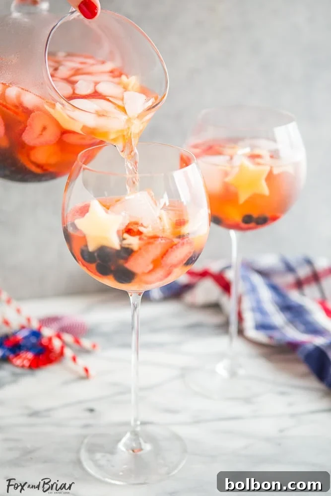 Kırmızı, Beyaz ve Mavi Şarap Punçları 5 Individual serving of Red, White, and Blue Wine Sparkler, showcasing the layered fruit and star-shaped apple garnish.