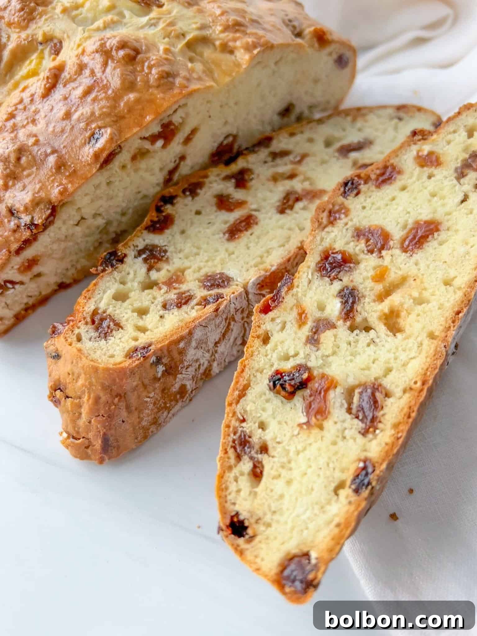 A freshly baked, golden brown Irish Soda Bread loaf with a scored 'X' on top, hinting at its tender interior. Perfect for St. Patrick's Day celebrations.