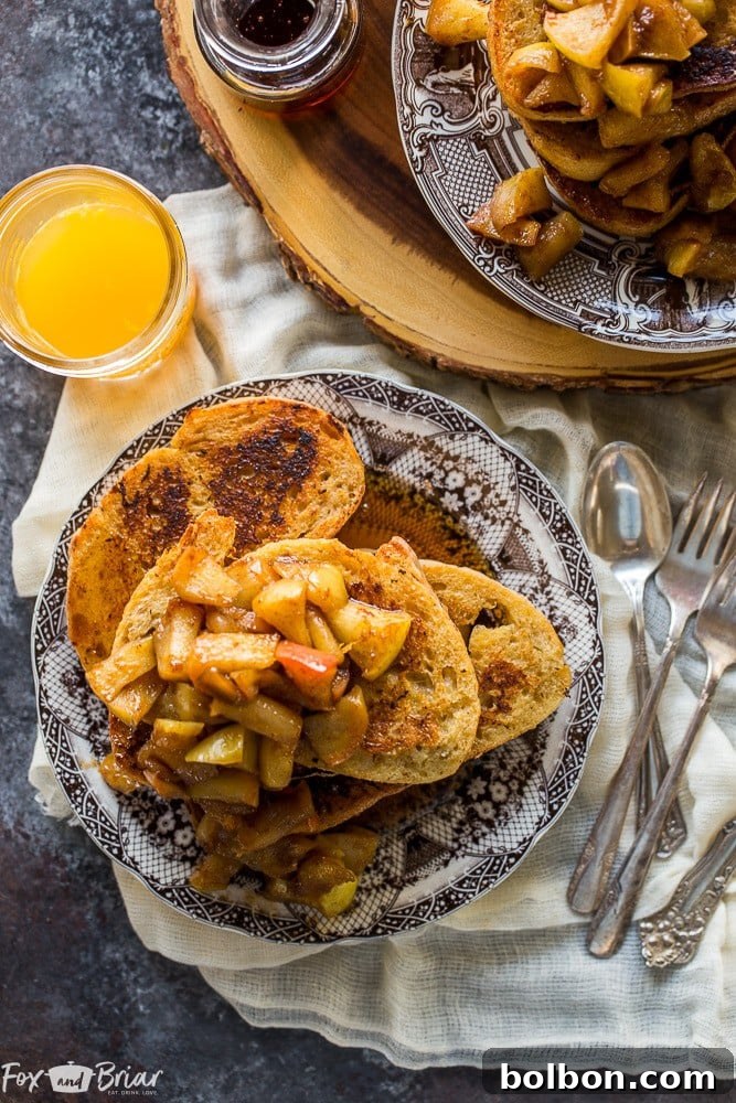 A beautifully plated serving of Apple Pie French Toast, garnished with fresh apple slices and maple syrup.
