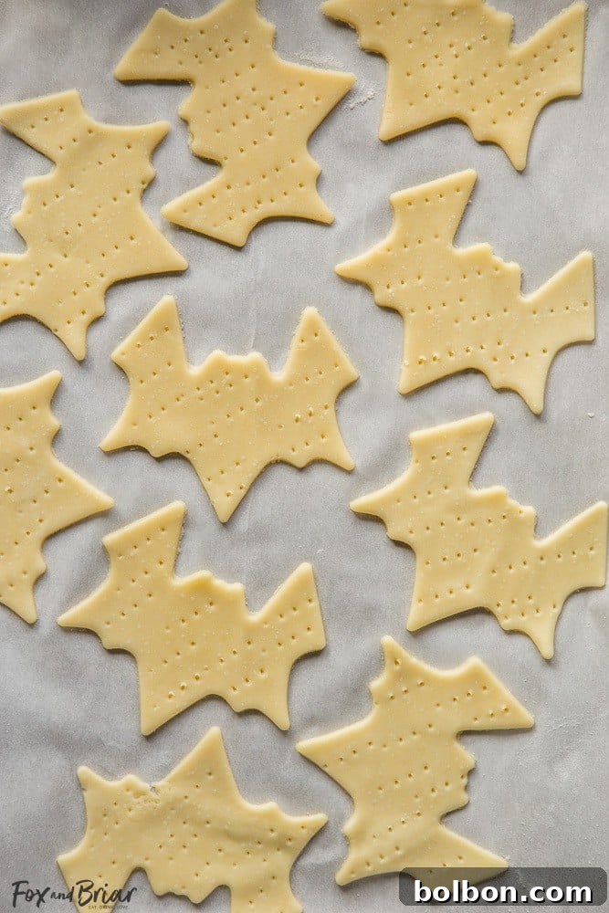 Spooktacular Surprise Crackers 3 Close-up of a stack of golden brown ghost-shaped Parmesan crackers with black sesame seed eyes, ready for a Halloween party