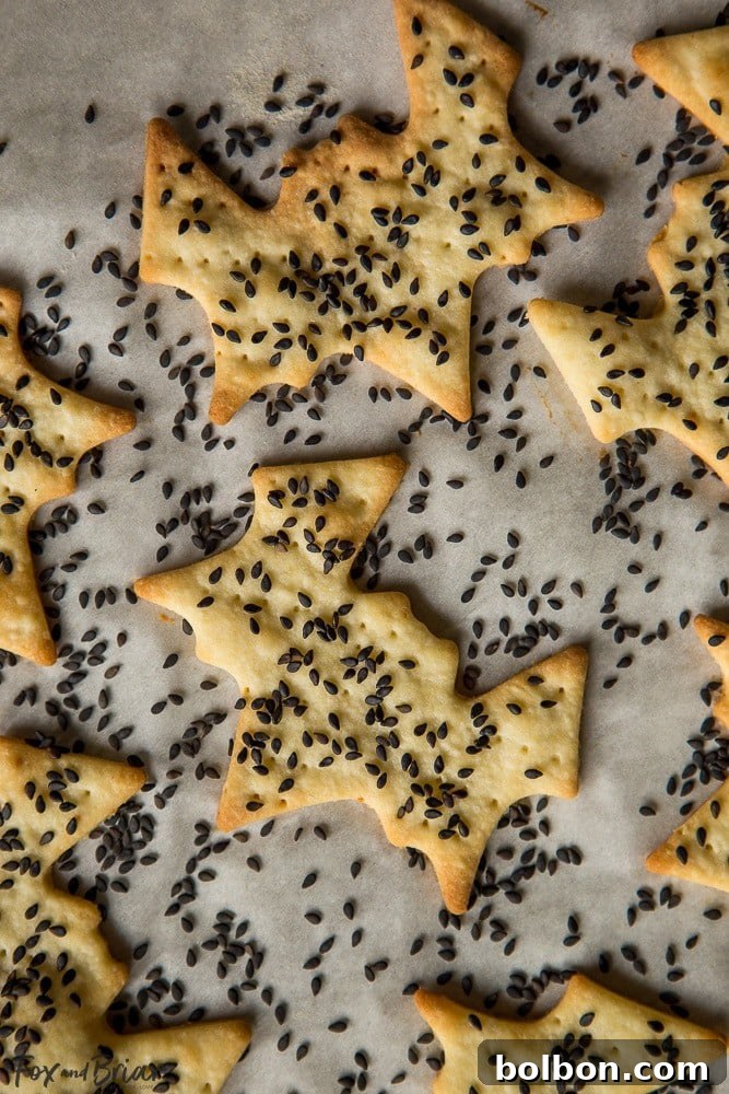 Spooktacular Surprise Crackers 4 A beautifully arranged Halloween cheese board featuring bat and ghost crackers, dark fruits, and various cheeses, perfect for a classy Halloween party