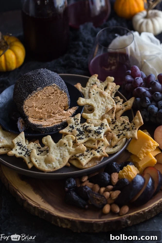 Close-up of the roasted garlic cheese ball showing its textured black poppy seed coating, accompanied by crackers, enhancing its appeal as a Halloween party food.