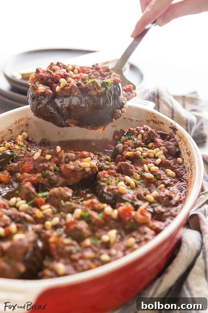 A visually appealing close-up of Meat Stuffed Eggplant (Bitten Jen) showcasing the rich lamb filling, roasted eggplant, and golden pine nuts. A perfect low-carb, Syrian main dish.