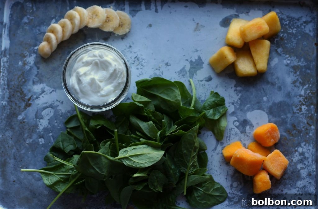 A tall glass of Tropical Green Smoothie with fresh fruit garnish.