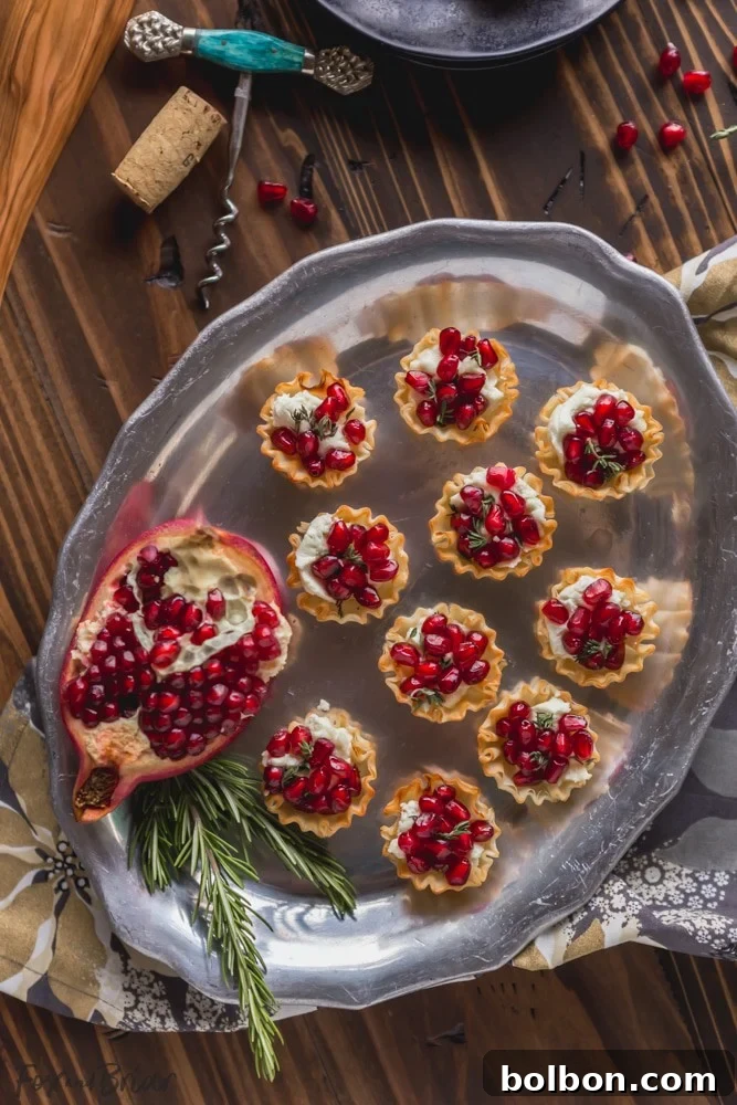 A tray of freshly baked Pomegranate Goat Cheese Bites, hot out of the oven, garnished with pomegranate arils and fresh thyme.