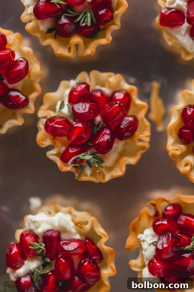 Pomegranate Goat Cheese Bites beautifully arranged on a white serving dish, garnished with fresh thyme, ready for a festive gathering.
