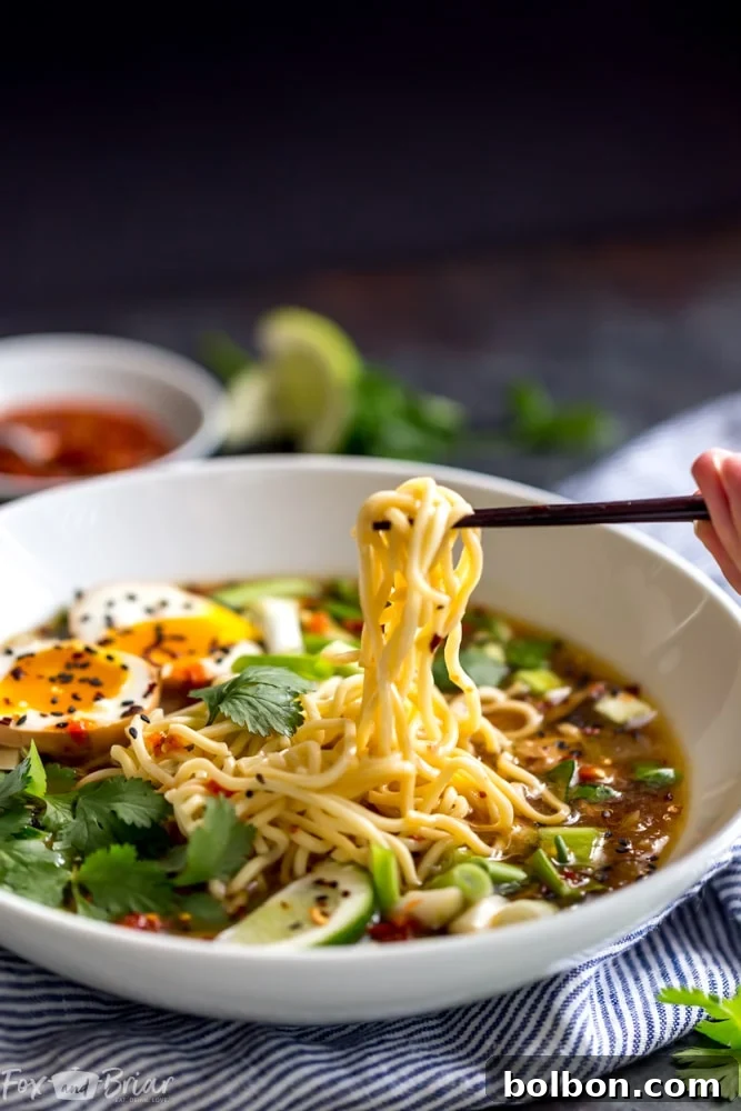 A beautifully presented bowl of Instant Pot Chicken Ramen, with steam gently rising, highlighting the generous toppings of green onions and a glistening soft-boiled egg. The depth of the broth is evident, promising a comforting and hearty meal.