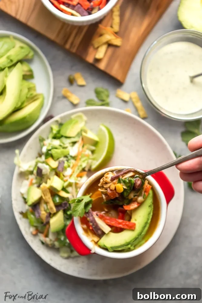 Wholesome Slow Cooker Chicken Tortilla Soup with a Fresh Southwest Salad 8 A perfectly portioned bowl of slow cooker chicken tortilla soup topped with avocado, cheese, and a lime wedge, served with a side of Southwest salad.