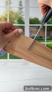 Doğanın Renkleriyle Paskalya Yumurtaları 4 A person is using scissors to cut a beige nylon stocking. The background shows a sunlit window with a view of greenery and a wooden fence.