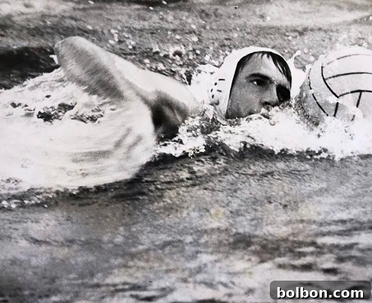 Effortless Greek Delights 2 A black and white photo captures a focused polo player, my father, swimming freestyle in a pool. He wears a cap and skillfully handles the ball, surrounded by dynamic splashes, embodying determination and athletic grace.