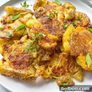 A plate of Crispy Smashed Potatoes, golden brown and perfectly cooked, garnished with fresh green herbs. These potatoes offer a rustic yet elegant presentation, ideal for any crispy smashed potato enthusiast.
