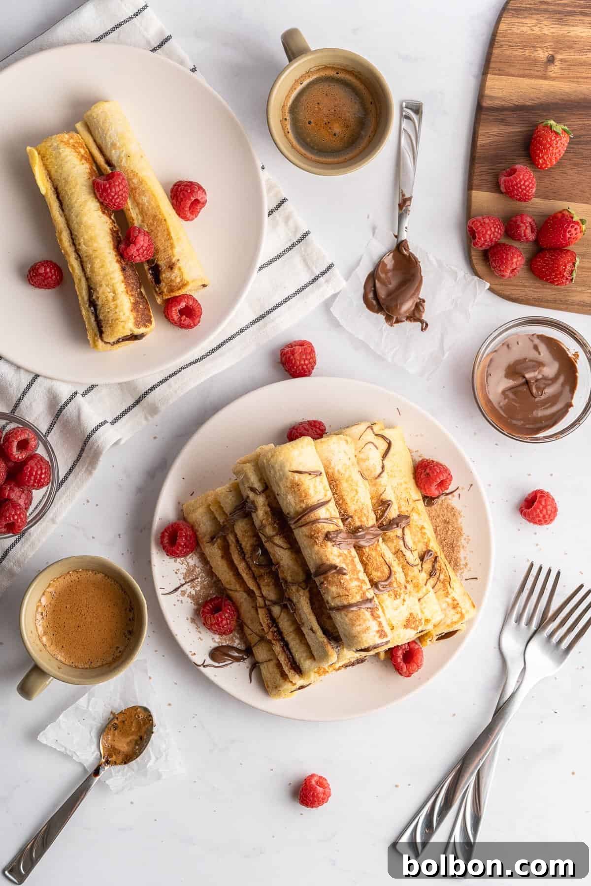 a beautiful table with cutlery, raspberries for garnish and French toast rolls that are plated 