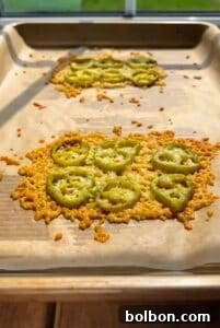 Jalapeño Hype Sandwich 6 A baking sheet holds two patches of melted, golden-brown cheese topped with sliced green tomatoes, cooling in sunlight from a nearby window.