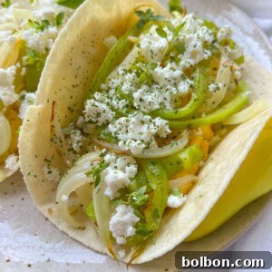 A close-up of a breakfast taco filled with sautéed onions, green peppers, crumbled white cheese, and fresh herbs on a light-colored plate.